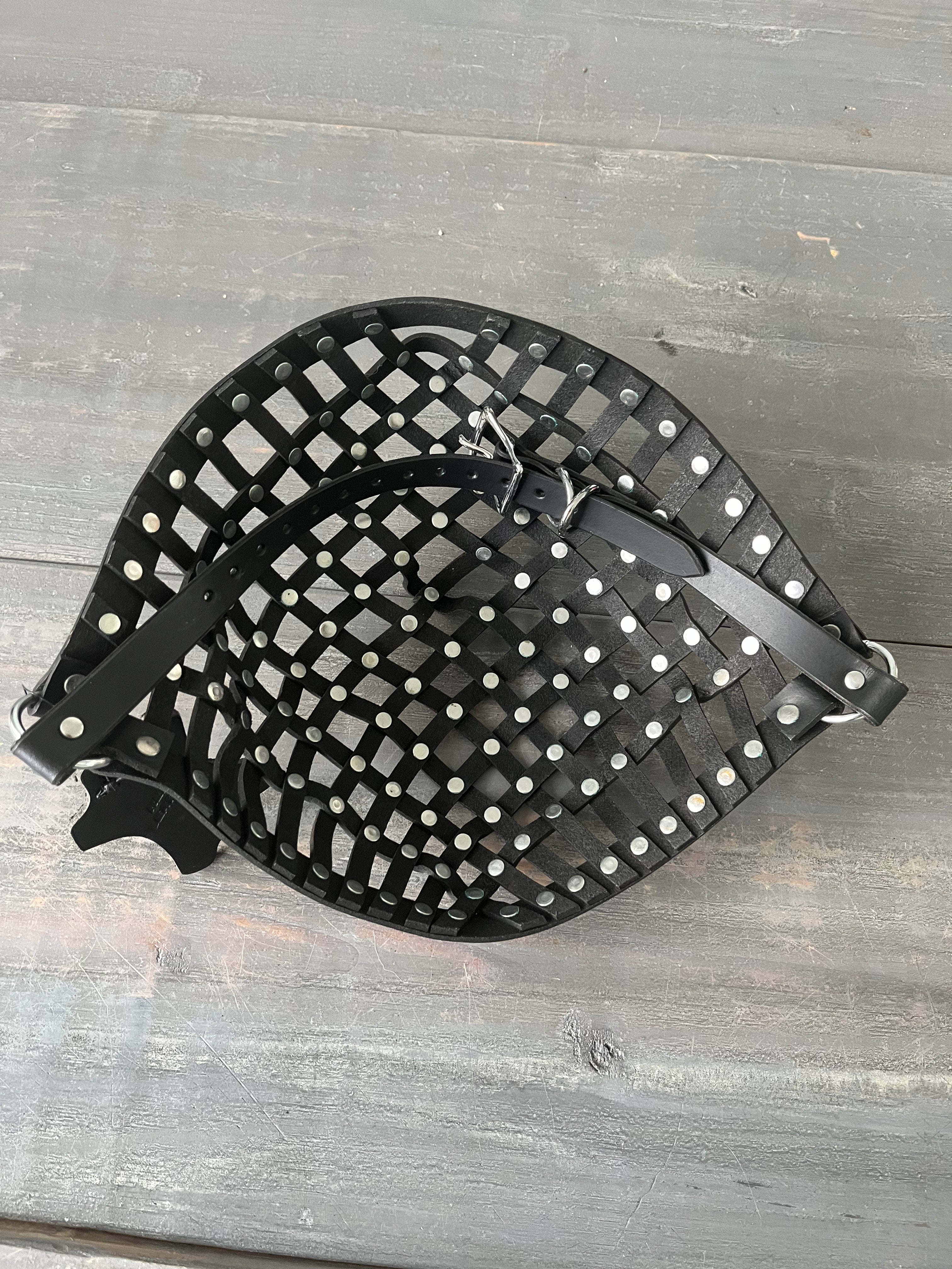 Photo showing a leather strapped mask with rivets laying on wooden table