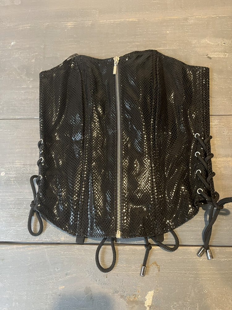 Black leather corset lying on wooden table. 