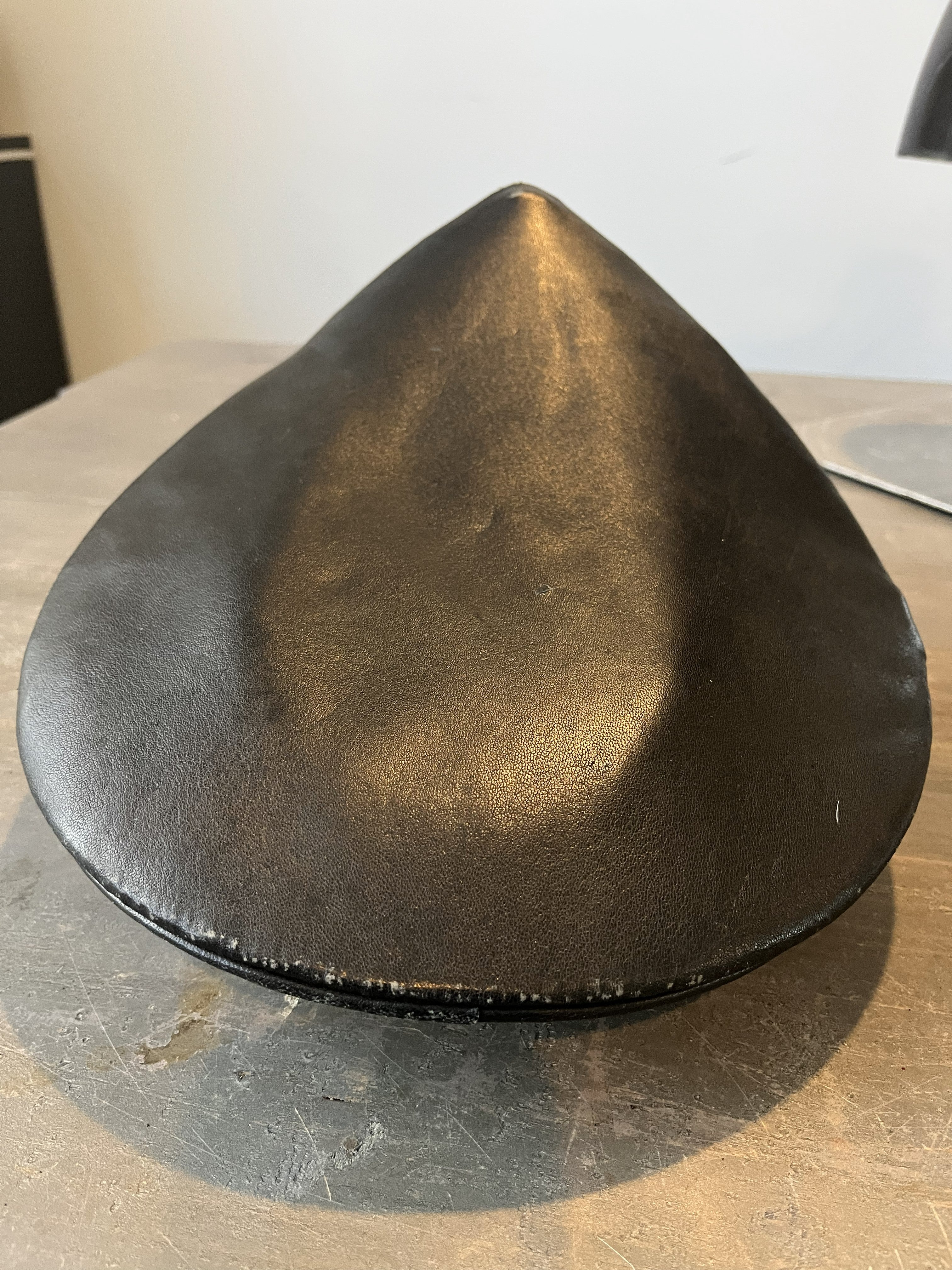 Black leather cone-shaped object on a wooden surface