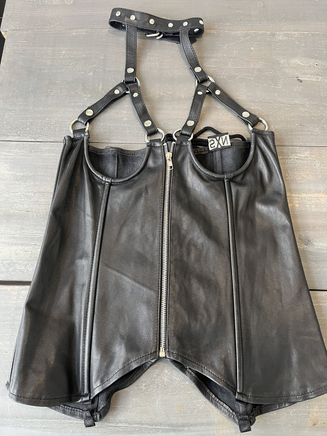 Black leather harness with studded details on a wooden surface