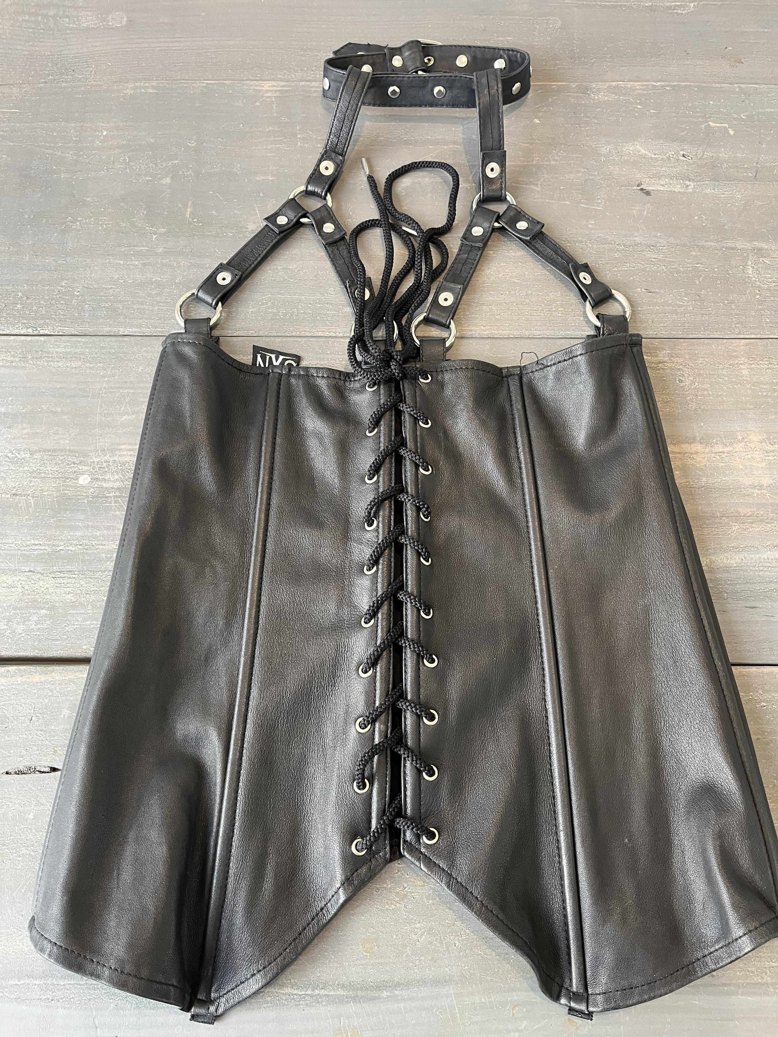 Black leather harness with straps on a wooden background