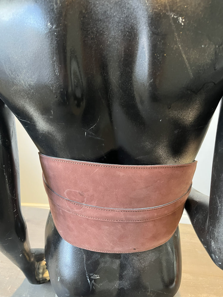 Mannequin torso with a brown leather harness on a neutral background