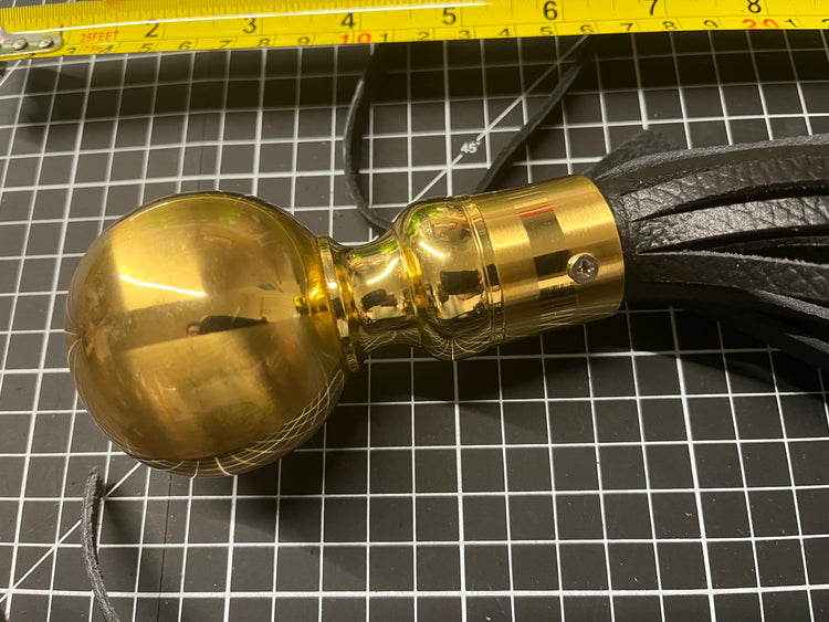 Gold tassel with black leather fringe on a grid background
