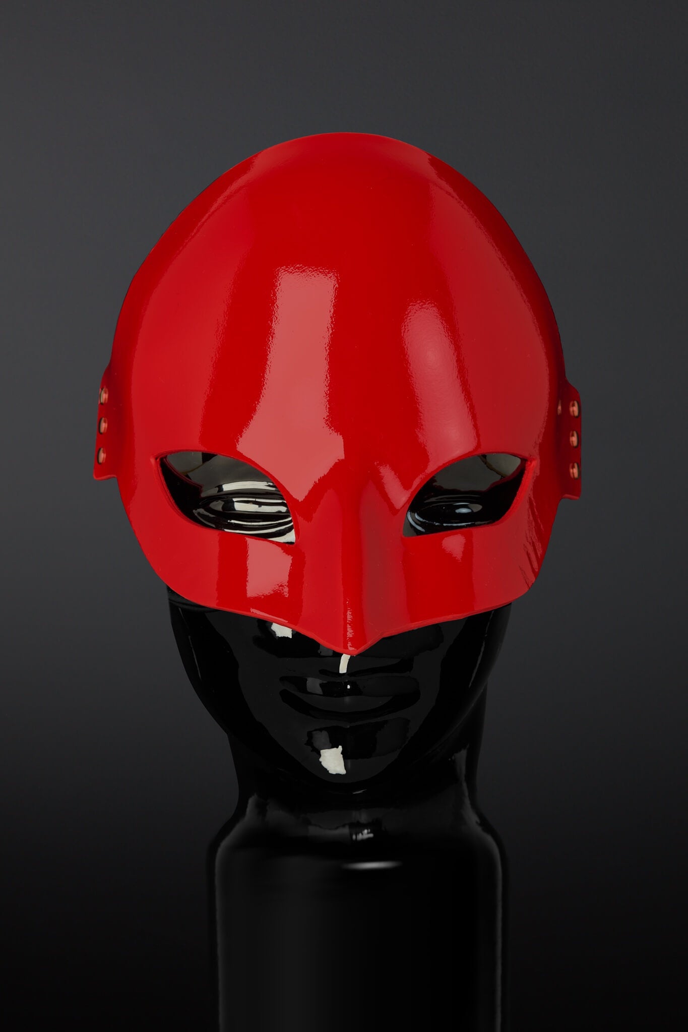 Red  mask on a black mannequin head against a dark background