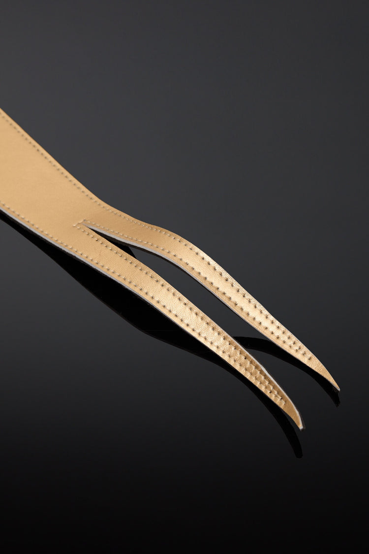 A gold-colored leather dragon tail whip with a textured, closeup of tail tip