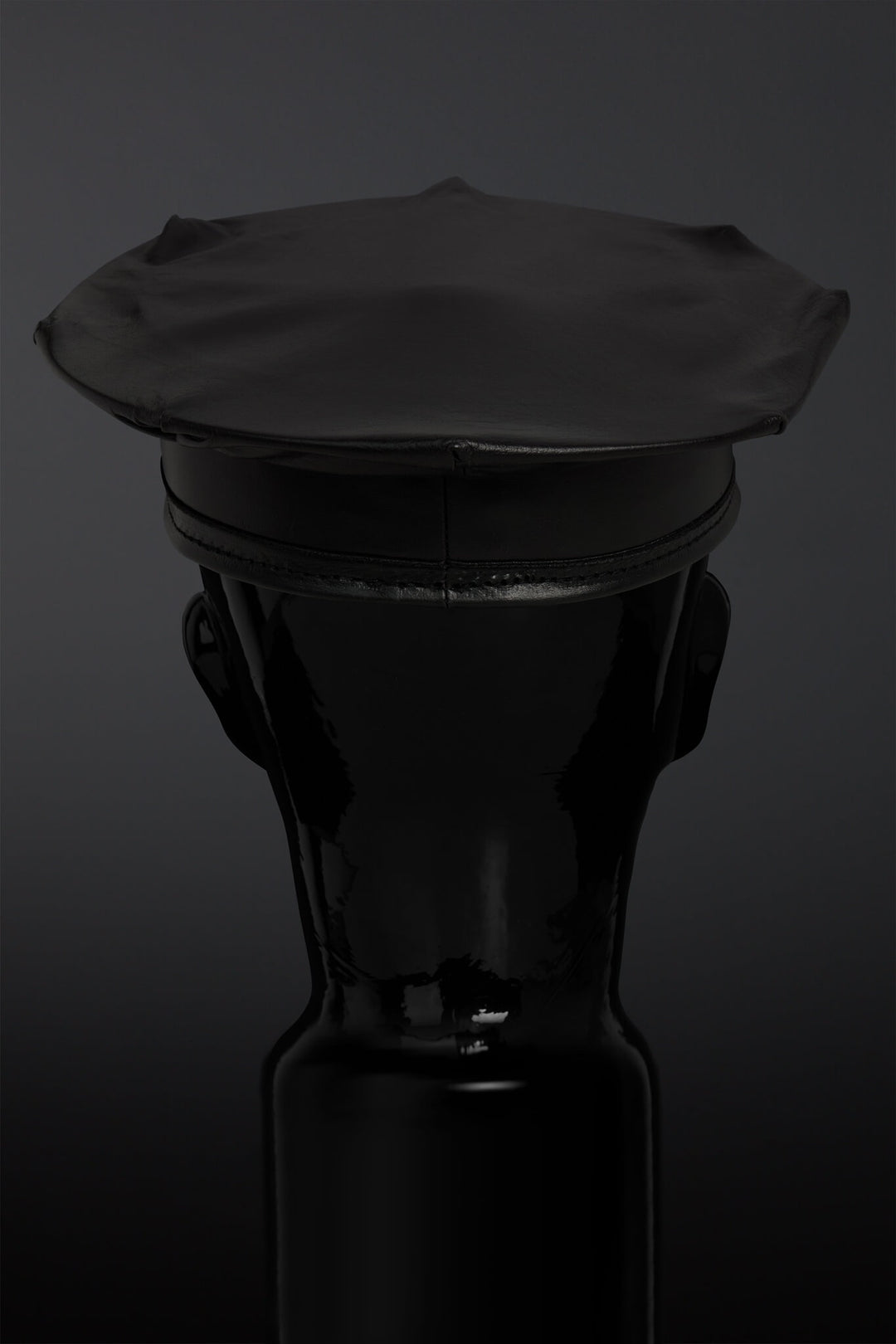 Black leather hat on a black mannequin against a dark background