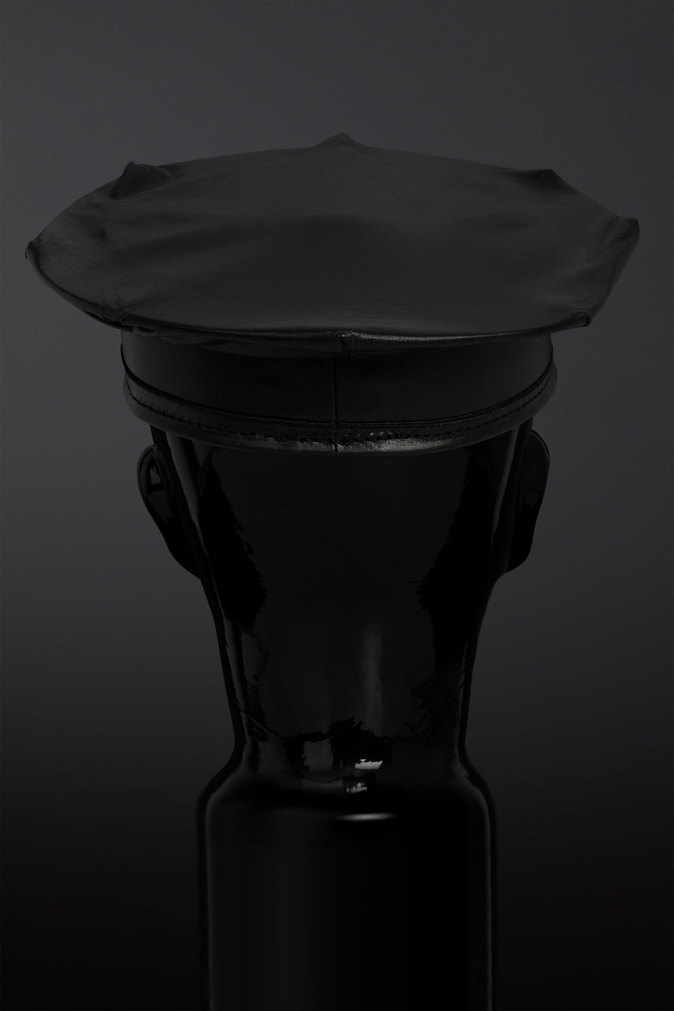Black leather hat on a black mannequin against a dark background