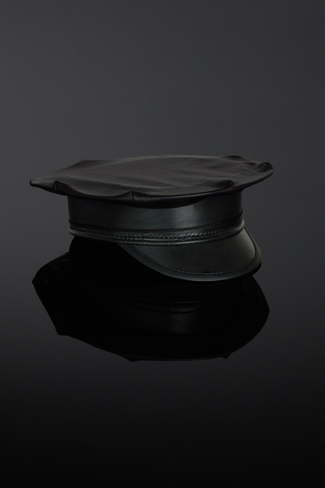 Black leather cap on a reflective black surface with a dark background