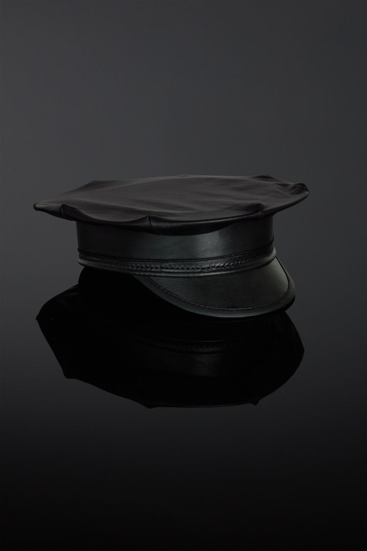 Black leather cap on a reflective black surface with a dark background