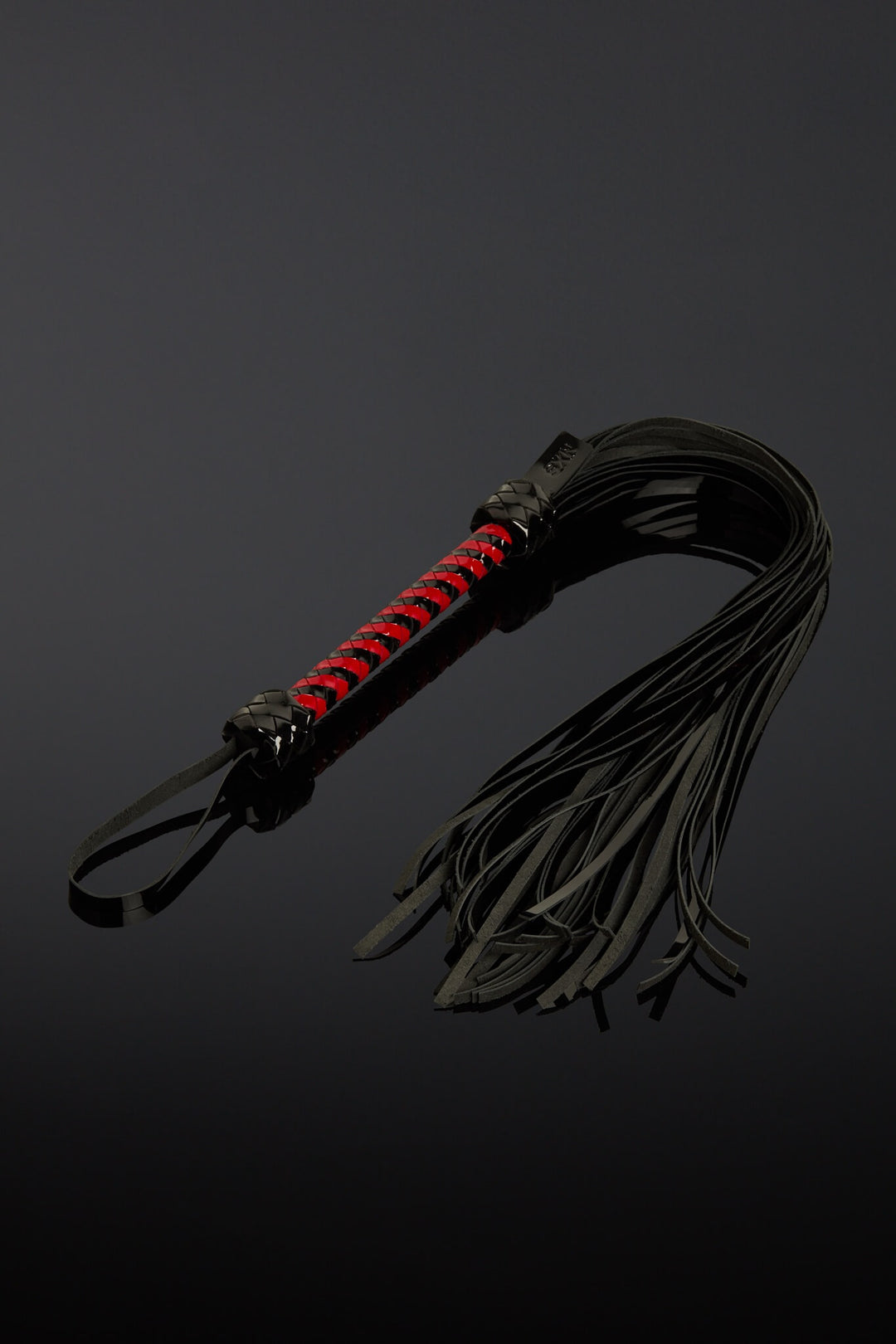 Black leather whip with red accents on a dark background