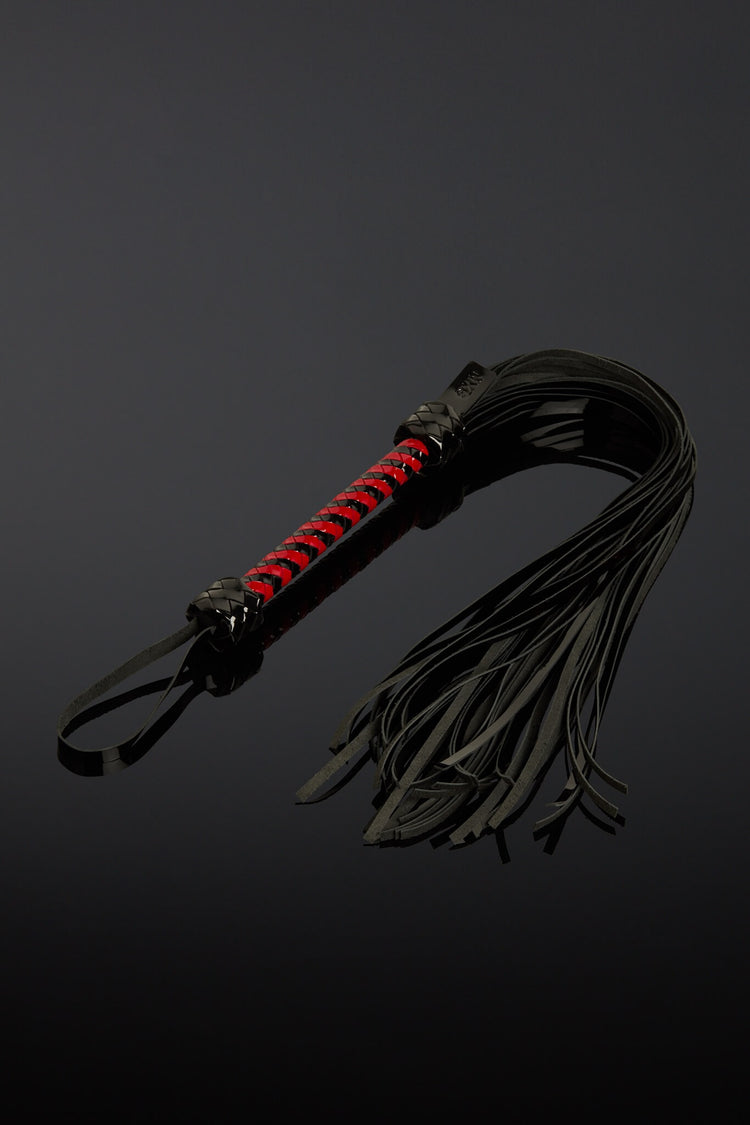 Black leather whip with red accents on a dark background