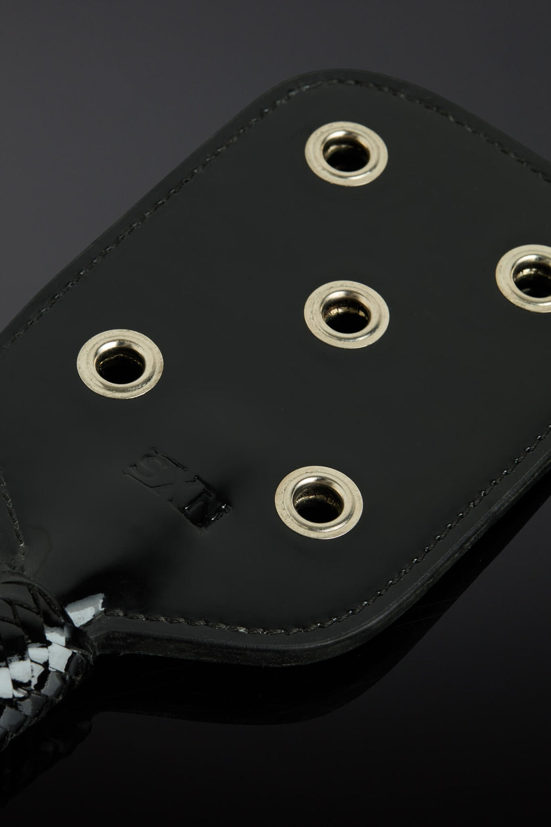 closeup shot of paddle showing metal eyelet openings. Taken on a black background