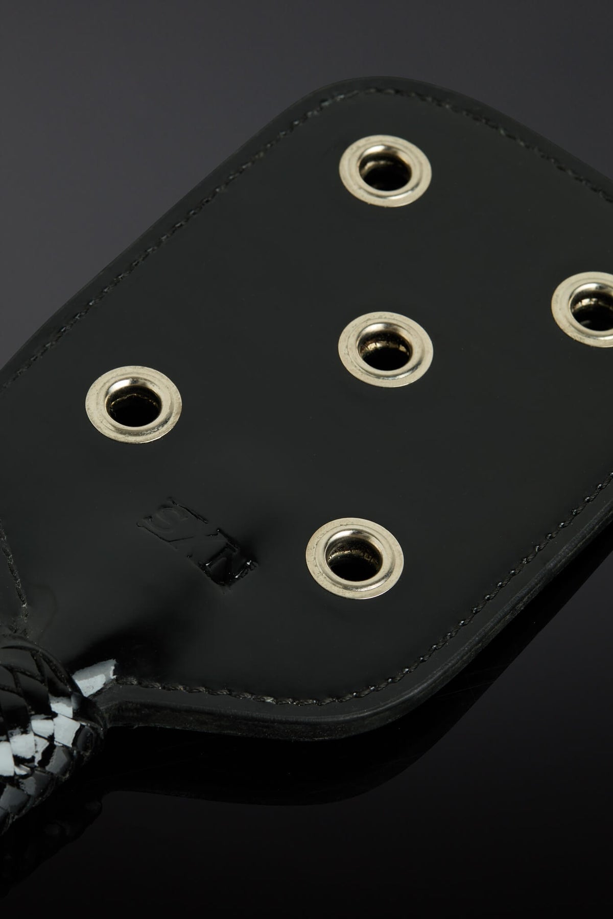 closeup shot of paddle showing metal eyelet openings. Taken on a black background