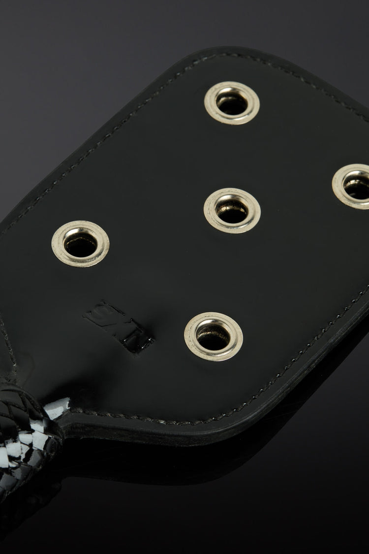 closeup shot of paddle showing metal eyelet openings. Taken on a black background