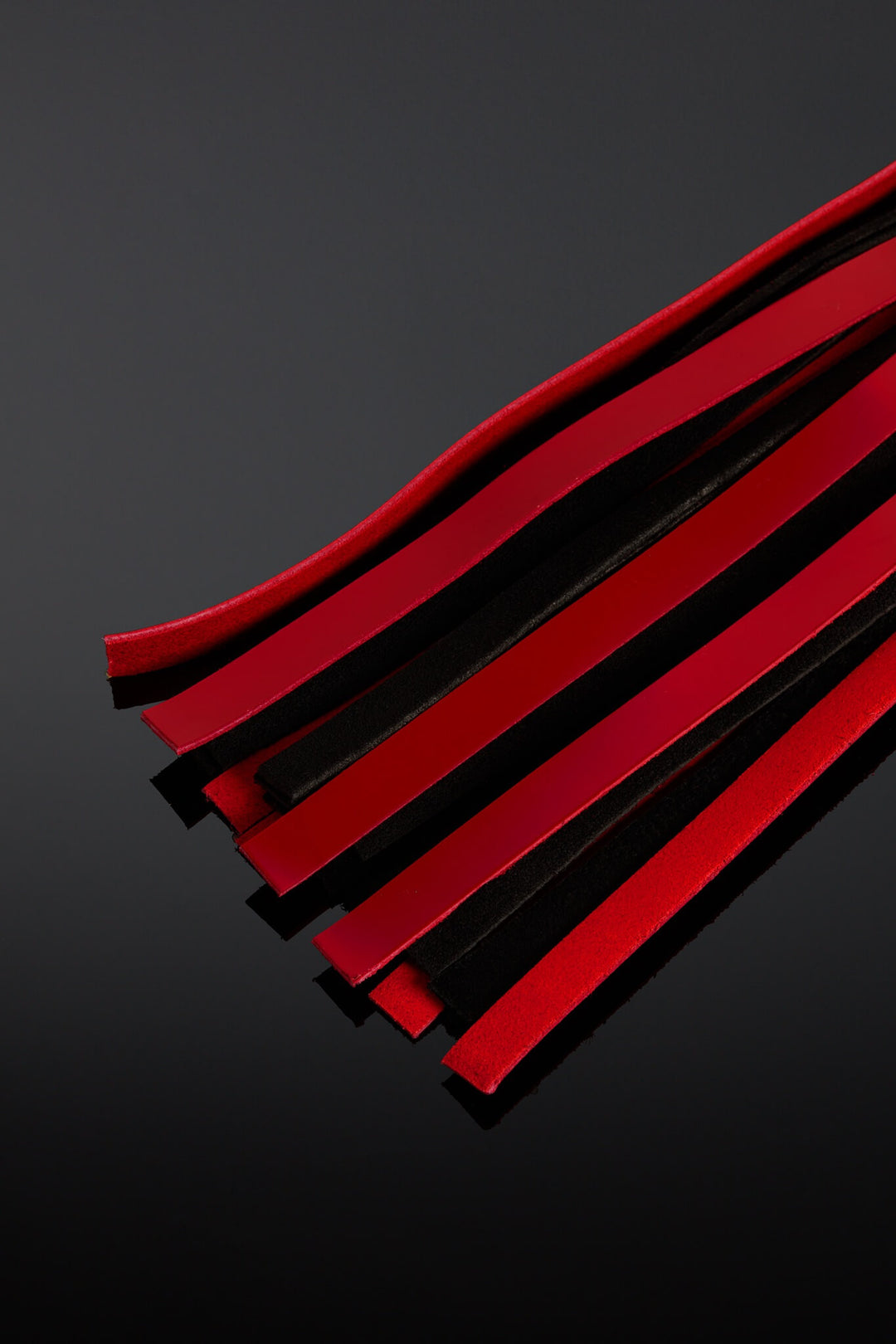 Red and black flogger taiis on a dark gray background