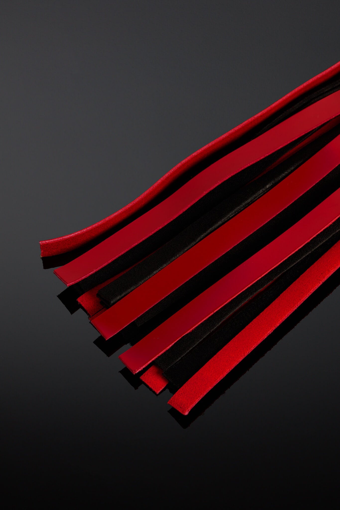 Red and black flogger taiis on a dark gray background