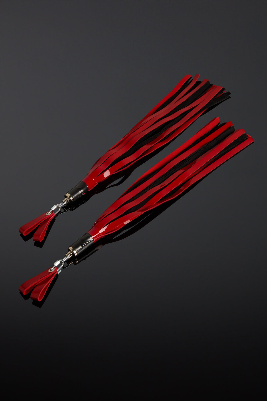 Two red leather floggers on a black background