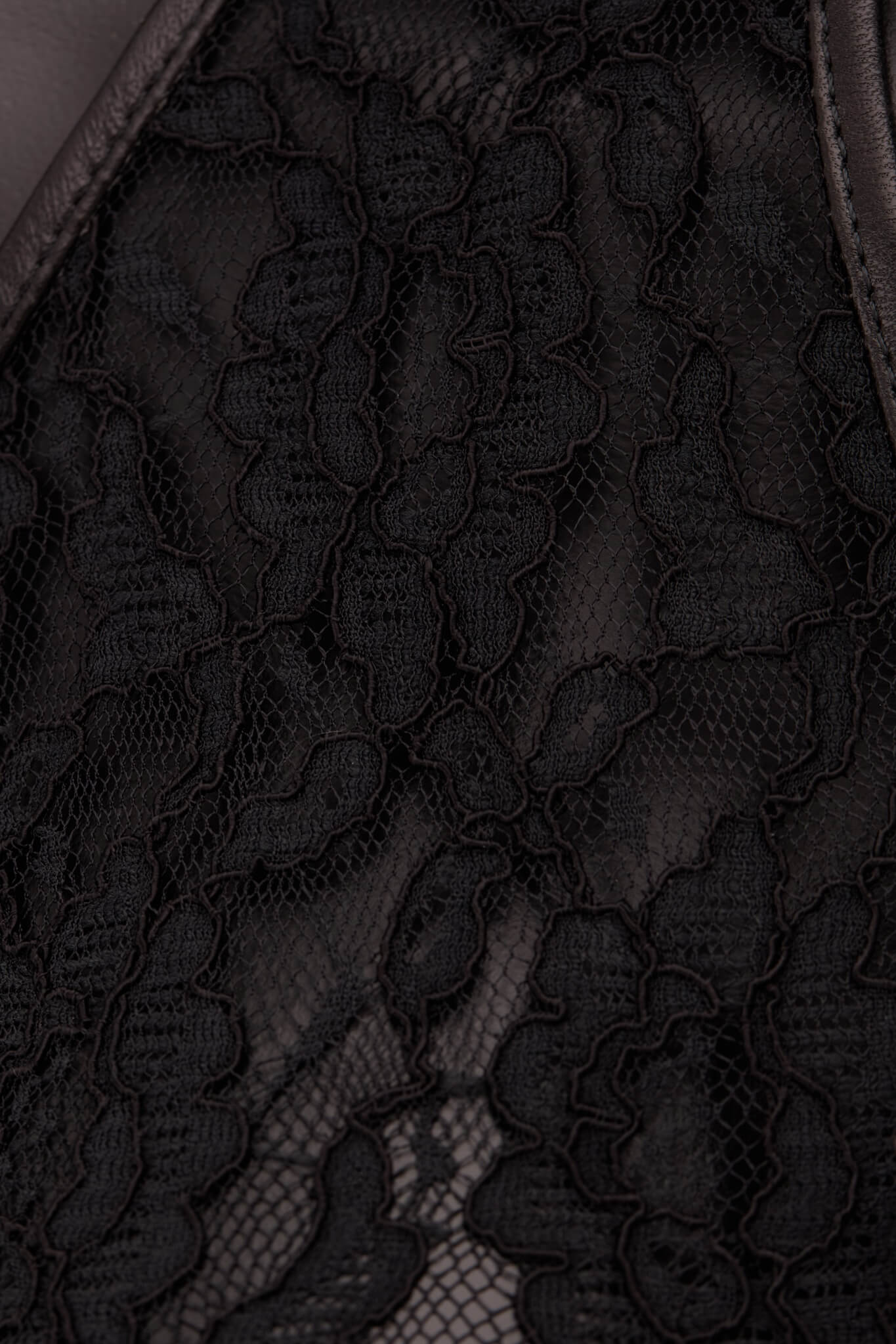 Close-up of black lace fabric with a sheer mesh overlay and scalloped floral pattern.