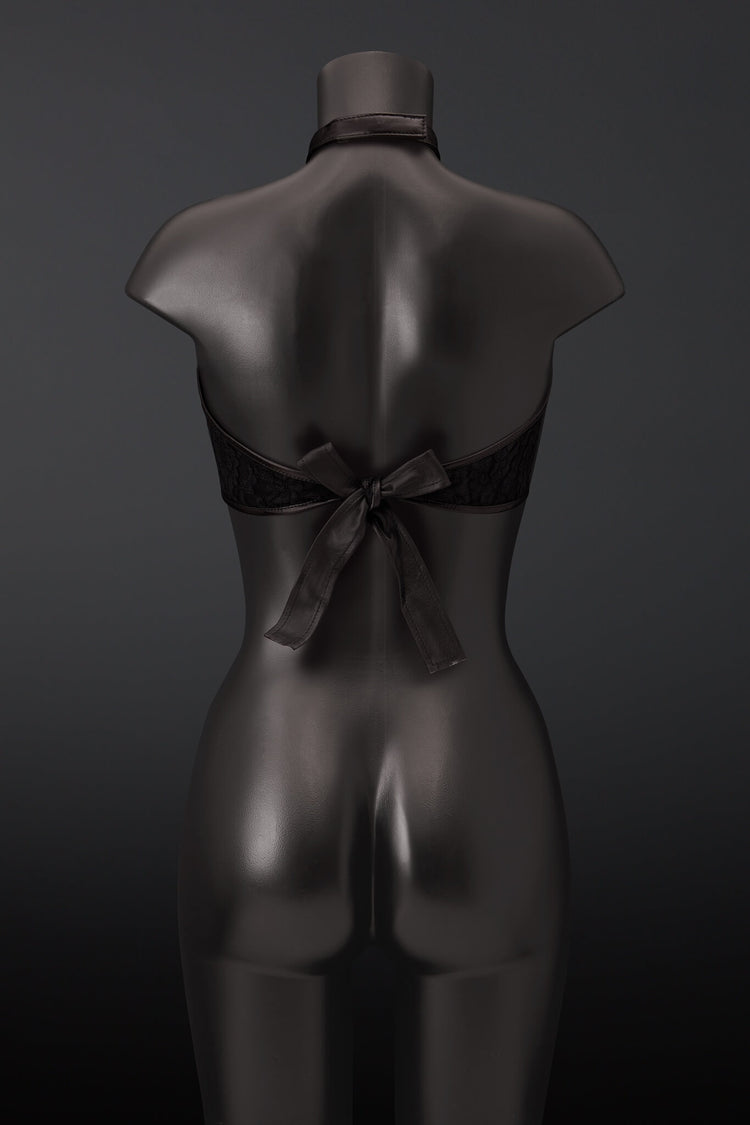 Black lace halter bra with a large leather back bow, displayed on a dark gray mannequin from the back against a dark gray background.