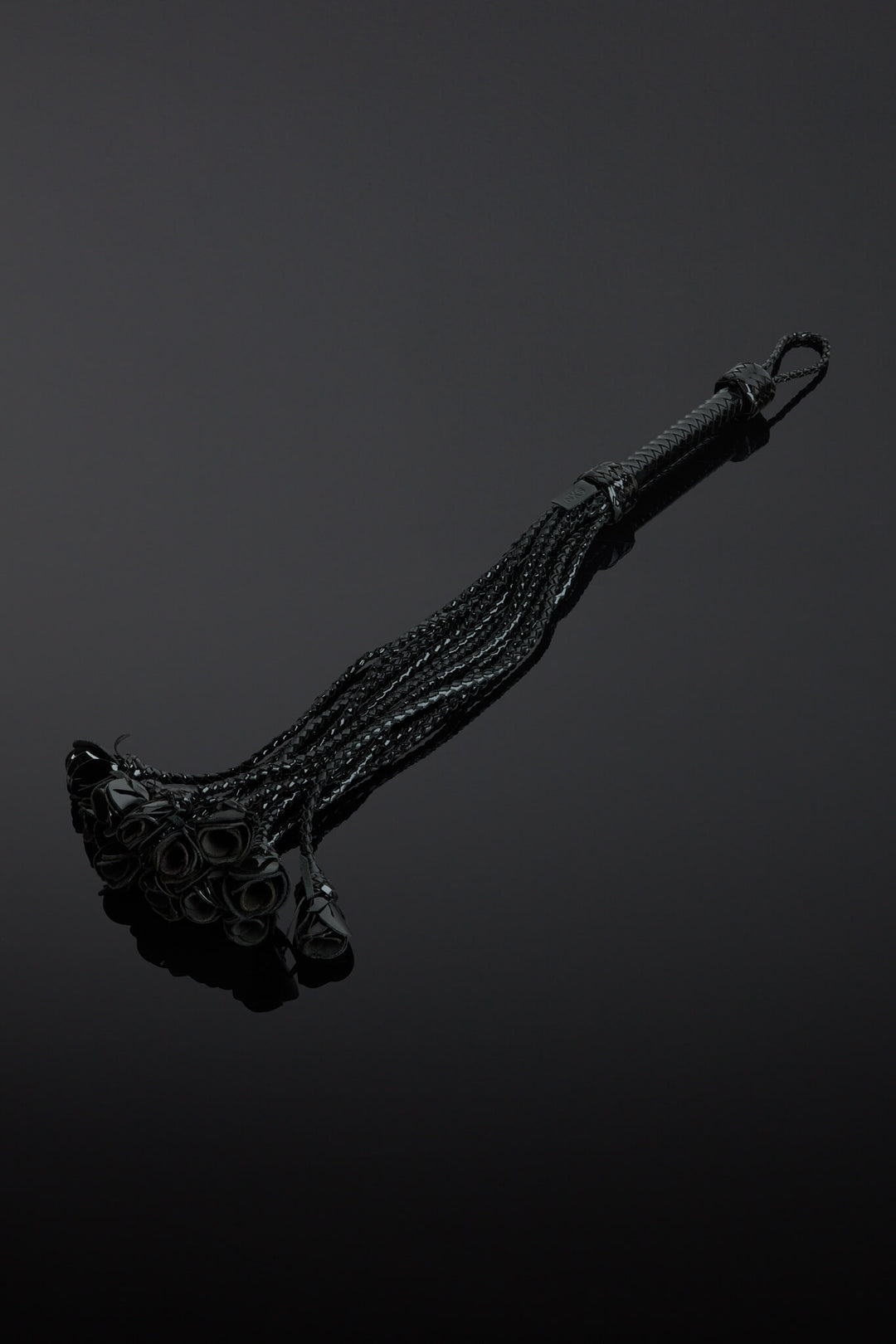 Black leather whip with decorative elements on a dark background