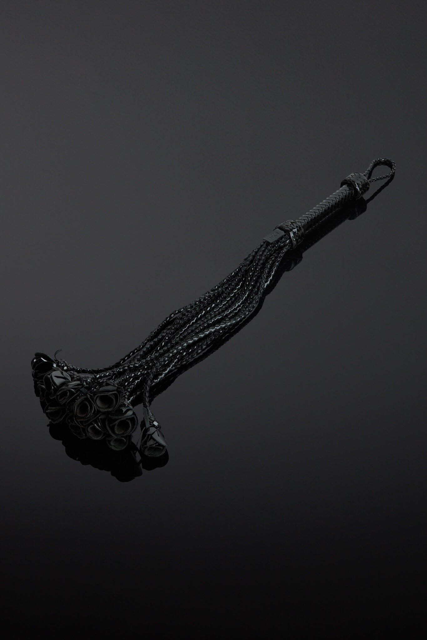 Black leather whip with decorative elements on a dark background
