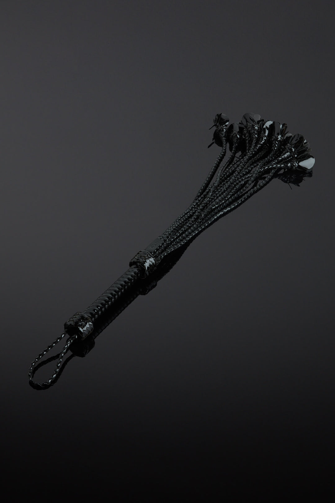 Black leather flogger on a dark background