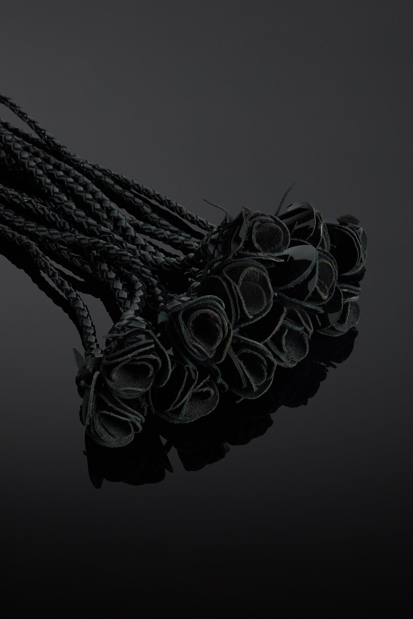 Bunch of flogger roses tails on a reflective surface with a dark background