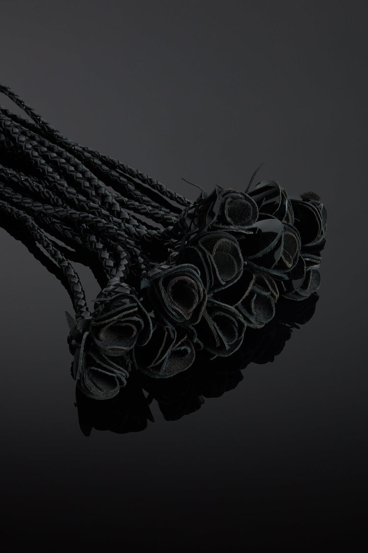 Bunch of flogger roses tails on a reflective surface with a dark background