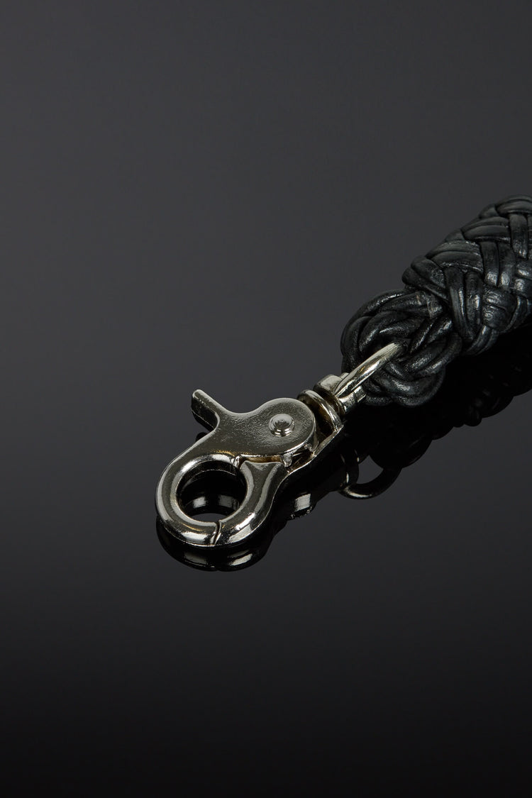 Black braided leather strap with silver clasp on a dark background