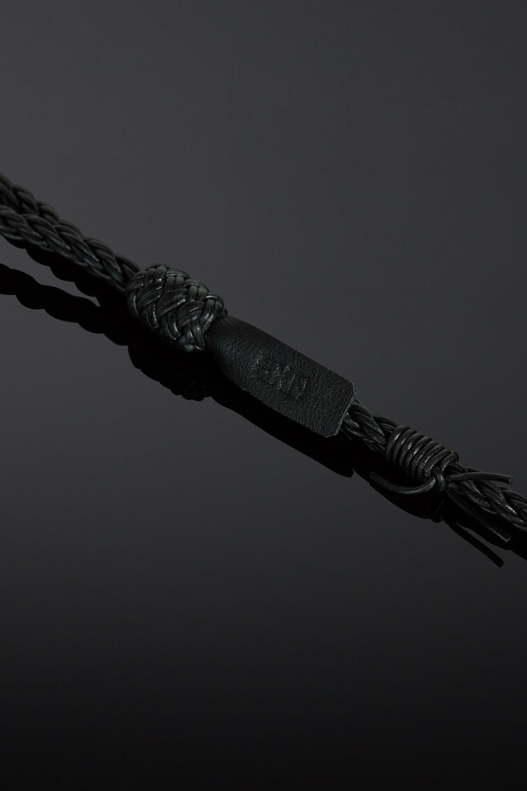 Black braided cord with a branded tag on a dark background