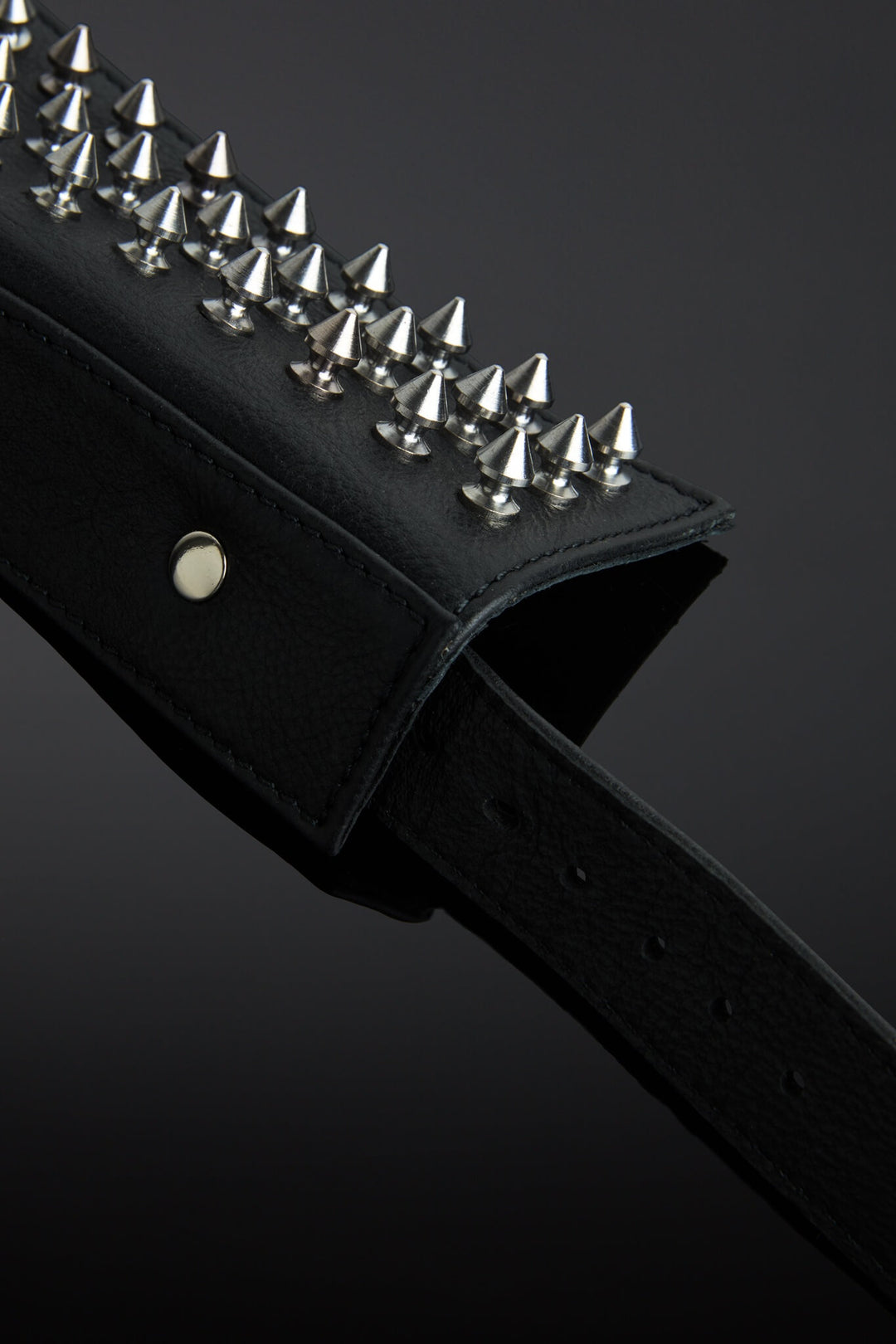 Black leather collar with silver spike details on a dark background