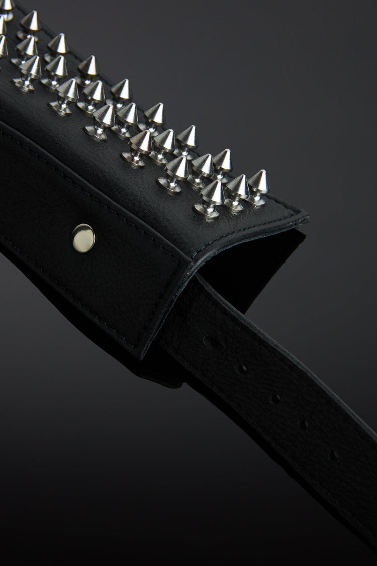 Black leather collar with silver spike details on a dark background