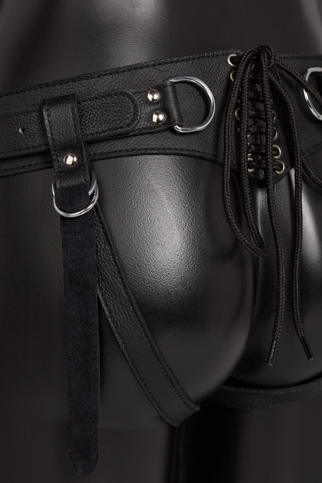 Black leather harness with metal buckles on a dark background