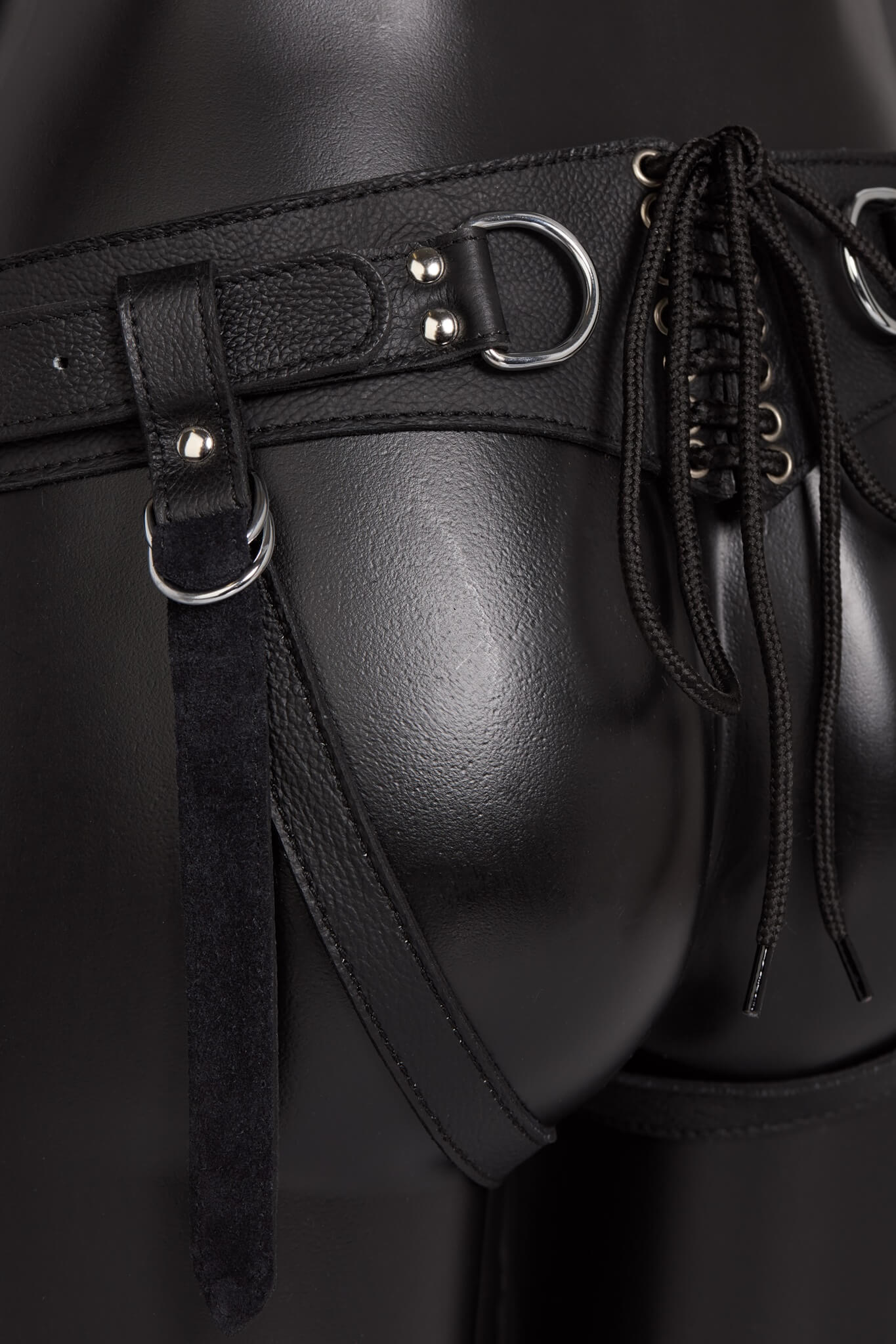 Black leather harness with metal buckles on a dark background