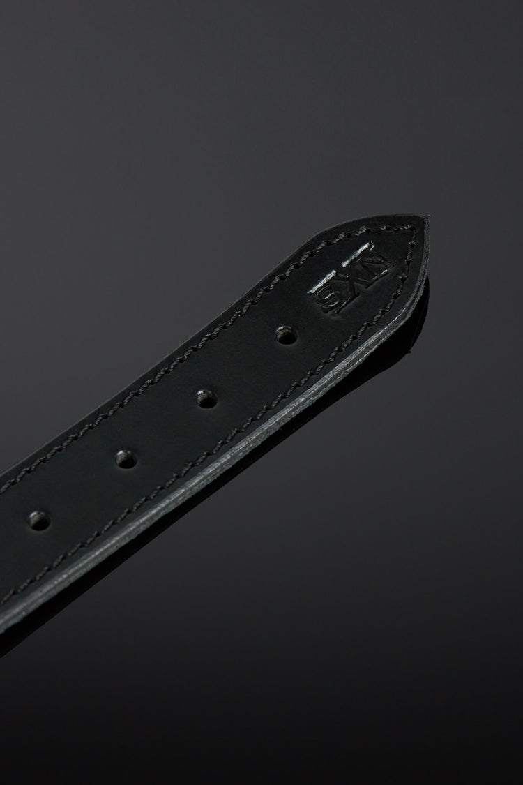 Black leather belt with brand logo on a dark background