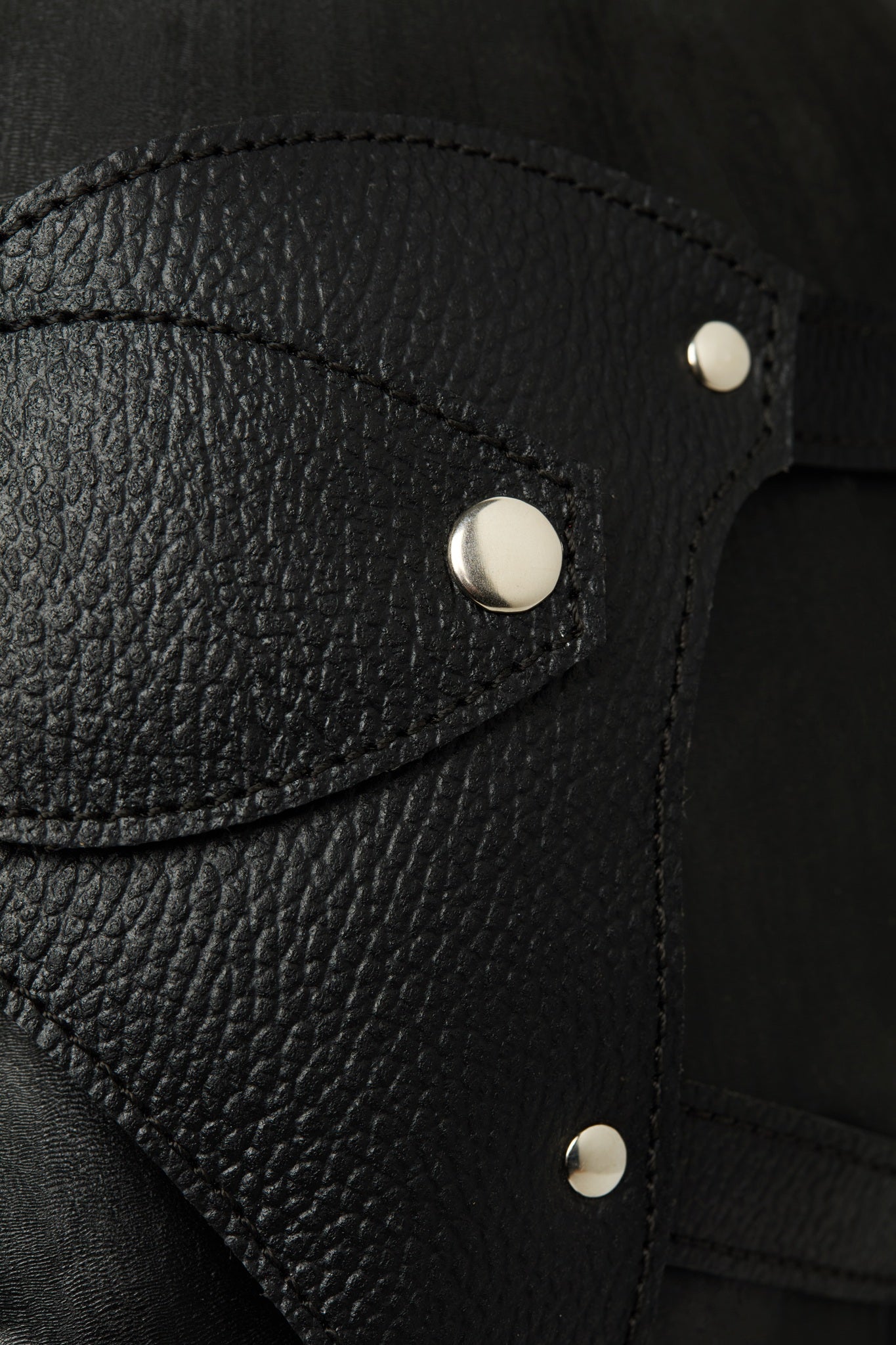 Close-up of black leather with silver buttons