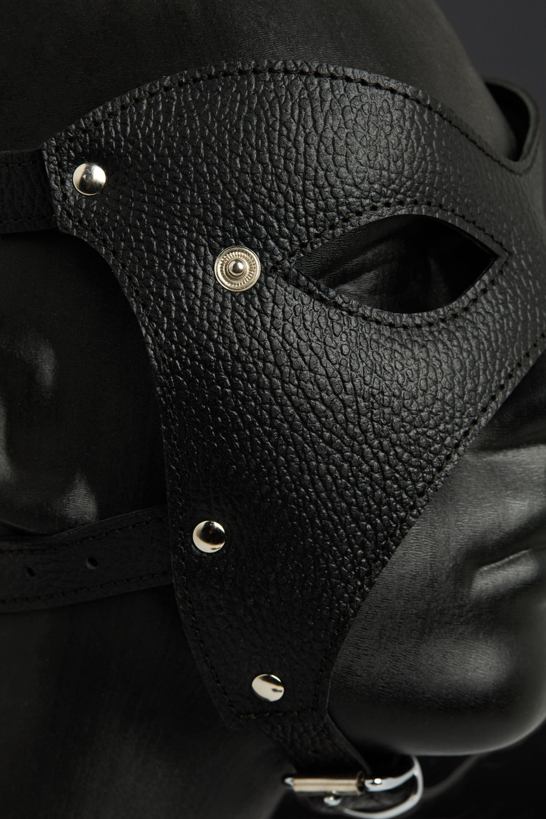 Black leather mask with metallic accents on a dark background
