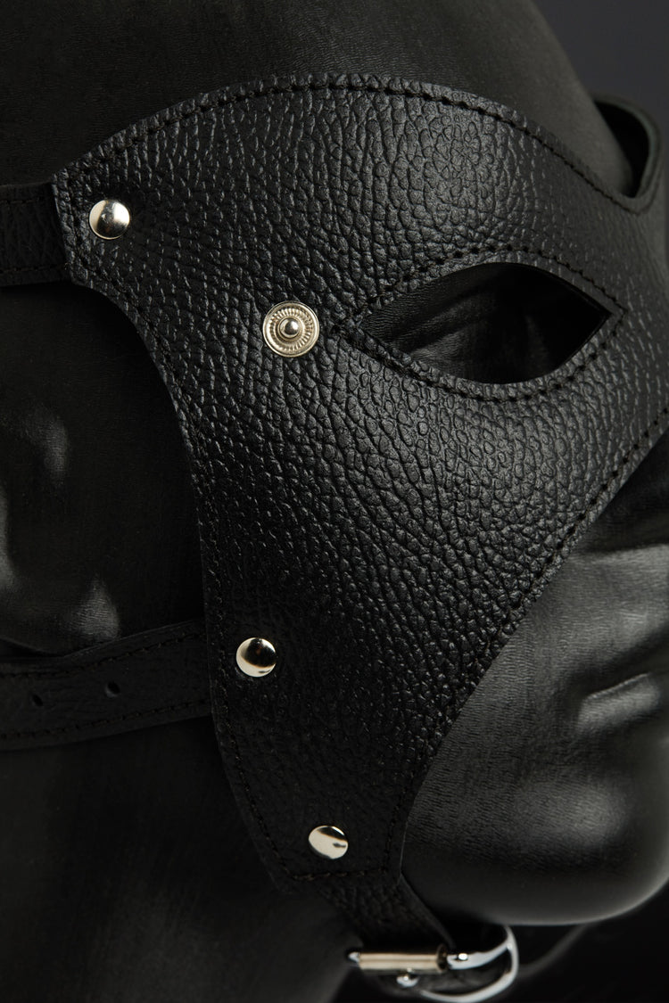 Black leather mask with metallic accents on a dark background