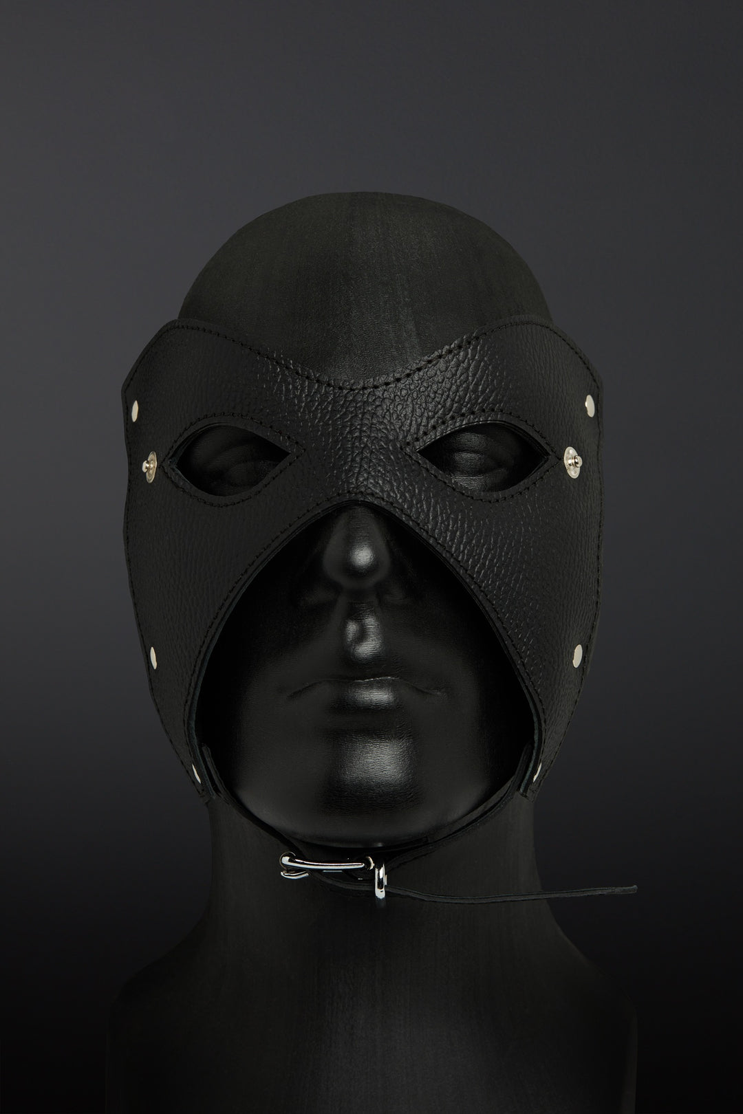 Black leather hood with eye and nose holes on a dark background