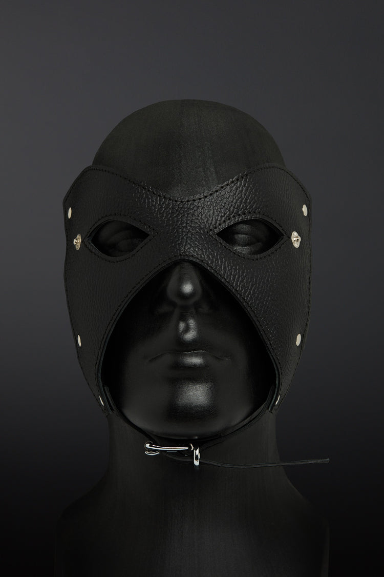 Black leather hood with eye and nose holes on a dark background